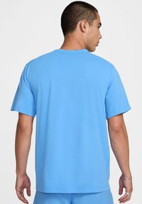 T-shirt bleu clair à manches courtes avec une coupe droite, en tissu lisse. Il présente un col rond et un design simple, sans logos visibles.