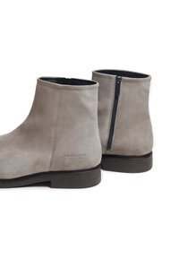 Botas de tobillo de ante gris con una cremallera negra y una suela texturizada, que presentan un branding sutil en el lateral y un forro interior suave.
