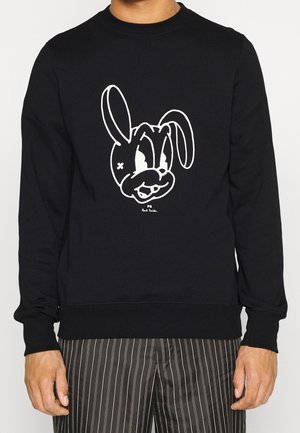 Schwarzer Sweatshirt mit großem weißem Cartoon-Hasen-Motiv auf der Vorderseite. Gerippter Ausschnitt und Bündchen, mit lockerem Schnitt. Getragene Hose mit vertikalen Streifen.