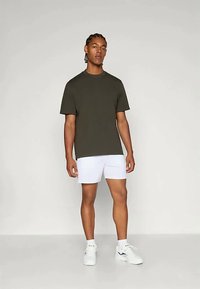 Tume roheline puuvillane t-särk ümarat kaelust, kombineeritud valgete lühikesed pükstega. Mudel kannab valgeid spordijalanõusid. Lihtne disain, lühikesed varrukad.