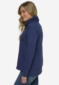 Felpa blu navy con collare alto, coulisse regolabile e polsini a costine. Texture morbida e vestibilità comoda. Dettaglio grafico sottile sul davanti.