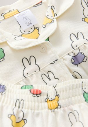 Cremefarbener Pyjama mit Miffy-Charakterdruck in verschiedenen Farben. Mit Knopfverschluss, Kragen und elastischem Bund. Weiche Textur.