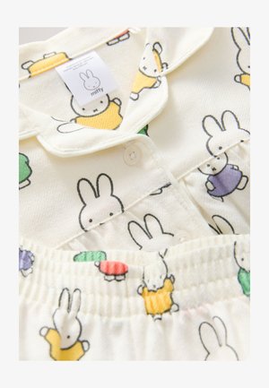 Krém színű pizsamaszett, amelyen a Miffy figura több színben látható. Patent záródású, galléros és rugalmas derékpánttal rendelkezik. Puha tapintású.