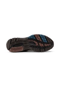 Melnās un brūnās Reebok zābaku zole ar zilu un brūnu gripu daļām uz balta fona, parādot protektora rakstu un zīmola nosaukumu.