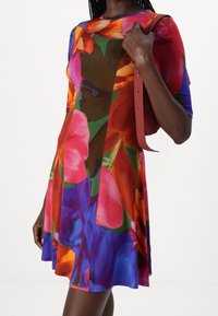 Robe florale colorée à encolure ronde, à manches courtes et à silhouette évasée. Accentuée par des teintes vives et audacieuses avec une texture douce.