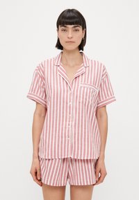 Ensemble de pyjama à manches courtes rayées en rose et blanc, avec des boutons, une poche poitrine et une coupe ample. Fabriqué en tissu doux et léger.