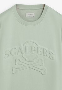 Sudadera verde claro con un logotipo texturizado y en relieve de "SCALPERS" y diseño de huesos cruzados. Presenta un cuello redondo acanalado y una tela suave.