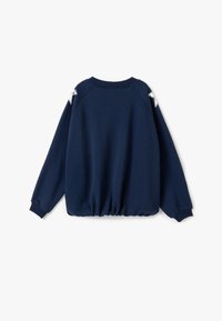 Granatowy sweatshirt z okrągłym dekoltem, elastycznym dołem i rękawami raglanowymi. Ma dwa białe akcenty w kształcie gwiazd na ramionach.