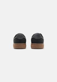 Schwarze Sneaker mit glatter Oberfläche, braunen Gummisohlen und einer strukturierten Ferse. Mit dem eingeprägten Levi's-Logo auf der Ferse.