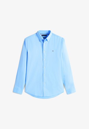 Lyseblå skjorte med knapper laget av bomull, med krage, lange ermer og en liten logo på venstre brystlomme.