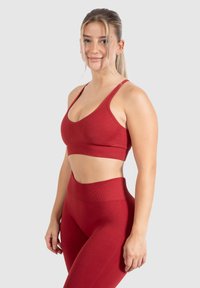 Rode sportbeha en high-waisted legging in een naadloos ontwerp. Zachte textuur met contourdetails langs de naden en een gladde afwerking.