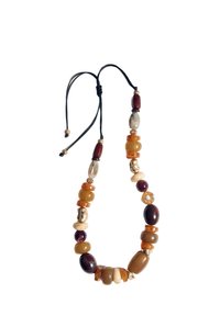 Collier en perles composé d'une variété de perles brunes et beiges de différentes formes et tailles, enfilées sur un cordon noir avec des nœuds coulissants.