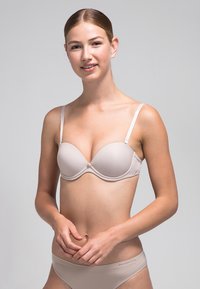 Sujetador push-up beige con copas acolchadas suaves y tirantes ajustables. Tejido suave, diseño sin costuras y un sutil cierre decorativo en el centro.