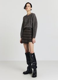 Gray cable-knit sweater, brown plaid shorts with an asymmetrical hem, and knee-high black glossy boots. Smooth texture and fitted design.