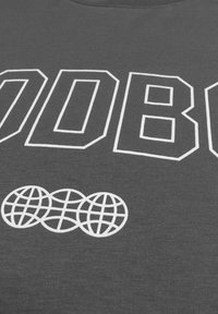 Dark gray cotton t-shirt with bold white text spelling "GOOD" and three globe icons below. Features ribbed texture and round neckline.