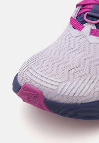 Sportssko med et teksturert, lys lilla mesh-overdel, rosa detaljer og såle i mørk blå gummi. Inkluderer en mønstret tåhette for godt grep.