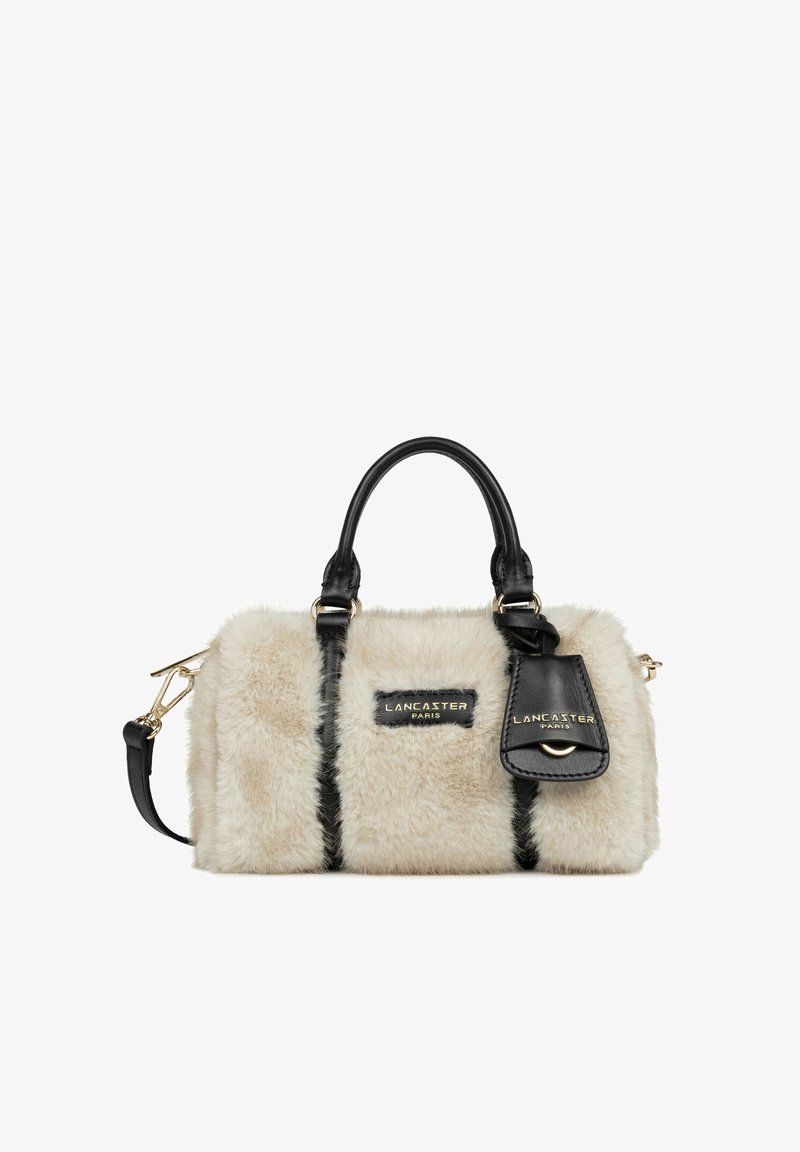 Petit sac à main beige en fourrure avec poignées en cuir noir et détails, ferrures dorées et logo Lancaster Paris sur le devant ainsi qu’une étiquette attachée.