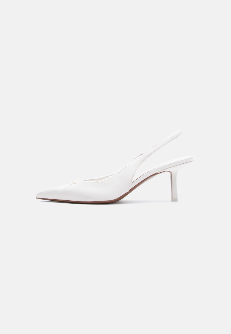 Chaussure pour femme en cuir blanc avec bride arrière, bout pointu, petit talon kitten bas et petit nœud décoratif sur le dessus, vue de profil latéral.