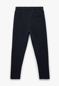Mørkeblå leggings lavet af tekstureret stof med et fiskebensmønster, der har en elastisk talje og en enkelt baglomme.