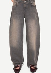 Breda ben i grå denimjeans med blekt struktur och knappstängning. Fickor på varje sida och en lös passform. Matchas med mörkare skor.