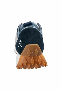 Sneaker z granatowym zamszowym piętkiem, białym logo i teksturowaną gumową podeszwą z wzorem diamentowym. Jasny materiał wierzchni.