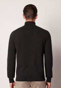 Schwarzer Strickpullover mit hohem Kragen, langen Ärmeln und figurbetonter Passform. Glatte Textur mit gerippten Bündchen und unterem Saum.