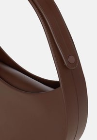 Brun håndtaske lavet af glat læderlignende materiale, med en buet form, bred håndtag og en trykknapdetalje. Minimalistisk design.