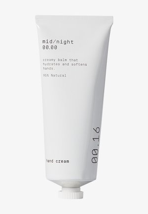 Hvit tube med håndkrem med en matt finish, med minimalistisk svart tekst. Inneholder detaljer som "kremet balsam" og "95 % naturlig."