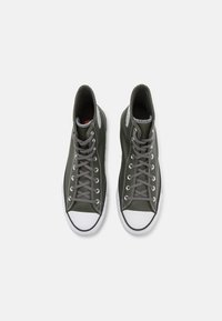 Sötétzöld bőrből készült, magas szárú sportcipő szürke fűzővel, fehér gumitalppal és texturált részletekkel az orrán és az oldalán.