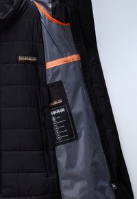 Czarna kurtka Napapijri otwarta, pokazująca szare wnętrze z pomarańczową lamówką oraz metkę z wypisanymi cechami tkaniny i logo marki.