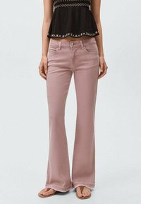 Ljusrosa utställda jeans i denim, med knappstängning, framfickor och en slät textur. Bärs med en svart topp och sandaler.