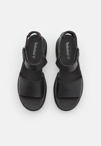 Paire de sandales Timberland noires avec une large bride avant et une bride de cheville réglable, vues de dessus sur fond blanc.