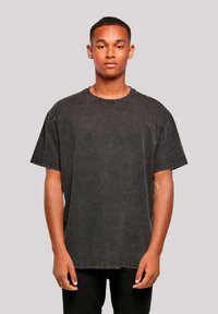 Black oversized T-shirt made of soft cotton. Features a round neck, short sleeves, and subtle stitching details on the hem and sleeves.