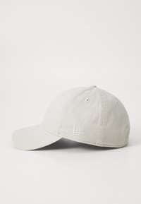 Baseballkappe aus leichtem beigem Baumwollstoff mit gebogenem Schirm, gesticktem Logo auf der Vorderseite und Belüftungsösen auf der Krone.