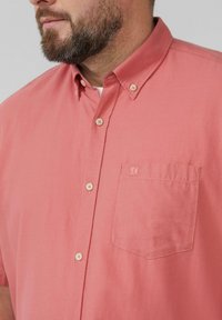 Koraalkleurig overhemd met korte mouwen, gemaakt van zachte, gestructureerde stof. Heeft een button-down kraag, een voorzak met logo en bijpassende knopen.