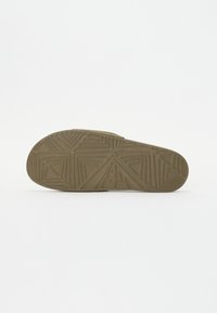 Schuhsohle mit strukturierter Oberfläche, die geometrische Muster und eine abgerundete Kante aufweist. Die Farbe ist ein gedämpftes Olivgrün mit matter Oberfläche.