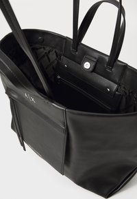 Borsa tote in pelle nera con doppi manici, ampio interno, chiusura a scatto e tasca con cerniera. Presenta un dettaglio logo sottile.