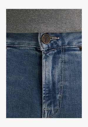 Blaue Denim-Jeans verfügen über einen Knopfverschluss mit einem Logo, einer leichten Waschung und kontrastierenden orangen Nähten entlang der Säume.