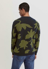 Strickpullover mit dunklem Marineblau als Grundfarbe und grünem Blumenmuster. Runder Ausschnitt, gerippte Bündchen und Saum, mittlere Dicke und weiche Textur.