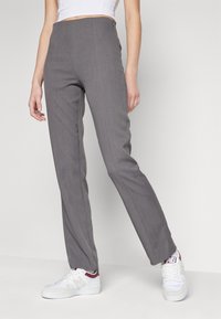 Szare dopasowane spodnie z wysokim stanem, o gładkiej fakturze i prostym kroju nogawki, połączone z białymi butami sportowymi.