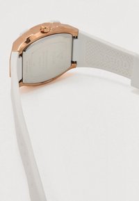 Witte siliconen horlogeband met een roségouden kast, afgeronde vorm, gestructureerde achterkant en gegraveerd merklogo op de band.