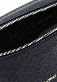 Borsa in pelle nera con texture, con zip metallica aperta che rivela una tasca interna con zip nera e una fodera in tessuto a righe.