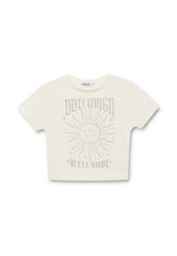 Camiseta recortada color crema hecha de algodón, con un gráfico del sol que tiene caras y el texto estilizado "BAD OWEN WELL BODE" en gris claro.