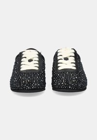 Zapatos negros con una superficie texturizada adornados con rhinestones plateados, con cordones blancos y un material negro suave alrededor de la abertura.