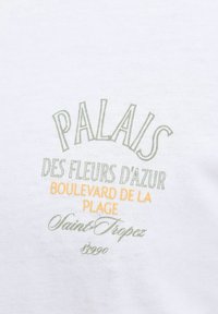 Κείμενο σε λευκό ύφασμα γράφει «PALAIS des fleurs d'azur Boulevard de la Plage Saint-Tropez 83990» με πράσινες και πορτοκαλί γραμματοσειρές.