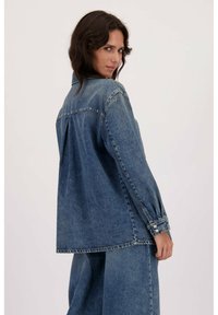 Denim jack in een lichte blauwe wassing, met lange mouwen, drukknoopmanchetten, een relaxte pasvorm en een rugpand met metalen accenten.