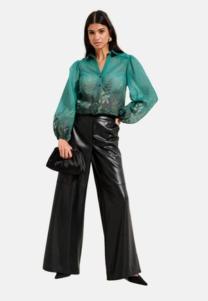 Transparent green blouse with floral embroidery, puffed sleeves, button-down front, paired with high-waisted black leather wide-leg pants and black clutch.
