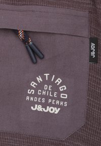Paarse stof met een gestructureerde oppervlakte met een cirkelvormig logo: "Santiago de Chile Andes Peaks J&Joy." Inclusief een patroonkoord.