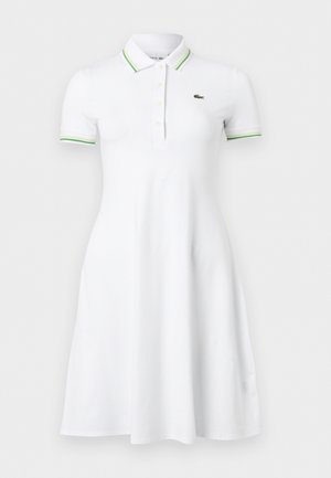 Λευκό κοντομάνικο φόρεμα πόλο με γιακά και μανσέτες σε πράσινες ρίγες, κούμπωμα με κουμπιά και μικρό πράσινο λογότυπο κροκόδειλου στο στήθος.