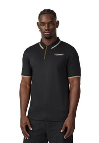 Czarna koszulka polo z pomarańczowymi i turkusowymi pasiastymi akcentami na kołnierzyku i rękawach. Zawiera logo McLaren na lewej stronie klatki piersiowej.